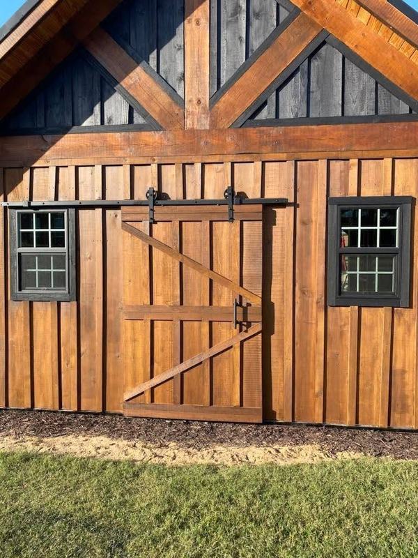 Stained board-and-batten siding with a sliding barn door and black-trimmed windows. Opens larger.
