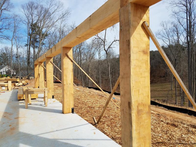 New timber posts and beams with angled braces standing on a concrete slab. Opens larger.