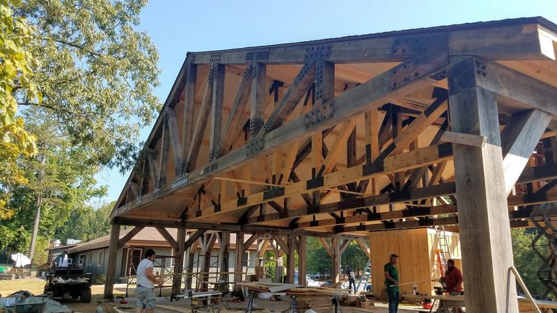 Large timber trusses with steel plate connectors on a pavilion under construction, crew working below