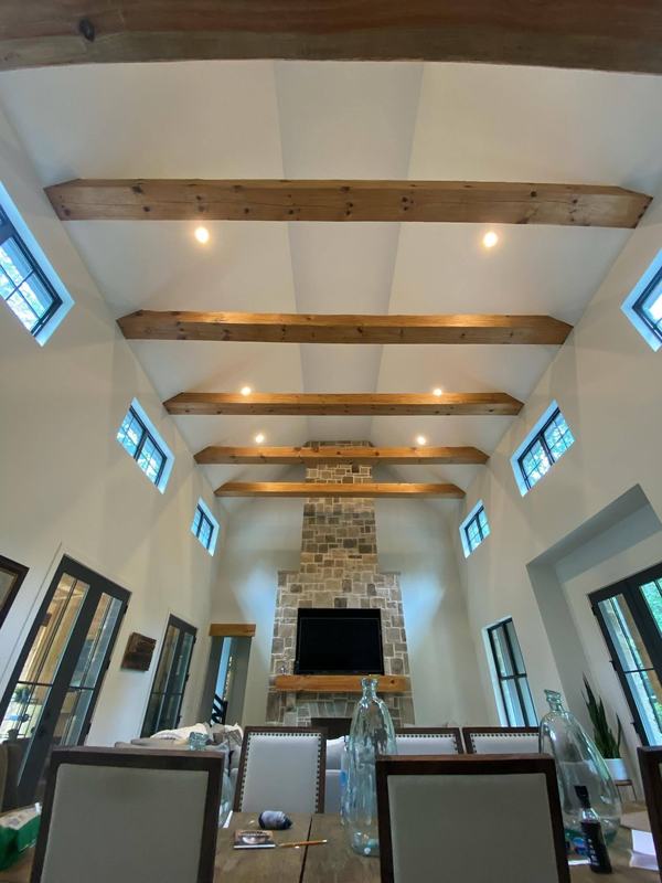 Wood beams across a tall white vaulted ceiling, leading to a stone fireplace. Opens larger.